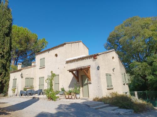 un grand bâtiment blanc avec des arbres devant lui dans l'établissement Le Mas de Rouvièges, à Le Pouget