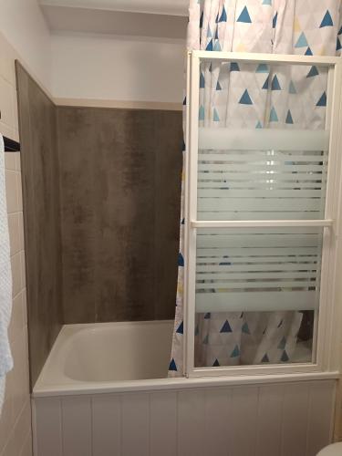 La salle de bains est pourvue d'une baignoire et d'un rideau de douche. dans l'établissement FACE MER PORNICHET BAIE DE LA BAULE GRAND STUDIO, à Pornichet