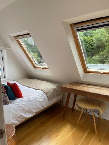a bedroom with a bed and a desk and two windows at Little Briar in Lyme Regis