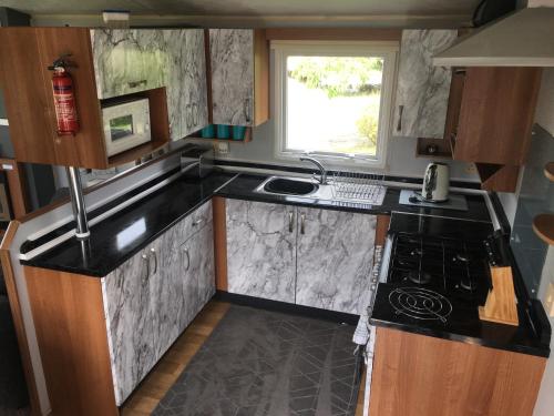 a small kitchen with a stove and a sink at Beautiful 3 bed caravan SouthviewPark Skegness in Skegness