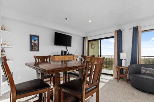 a dining room with a table and chairs and a television at Seaside Beach Club 204 in Seaside