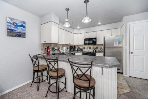 a kitchen with a counter with stools and a refrigerator at Seaside Beach Club 204 in Seaside