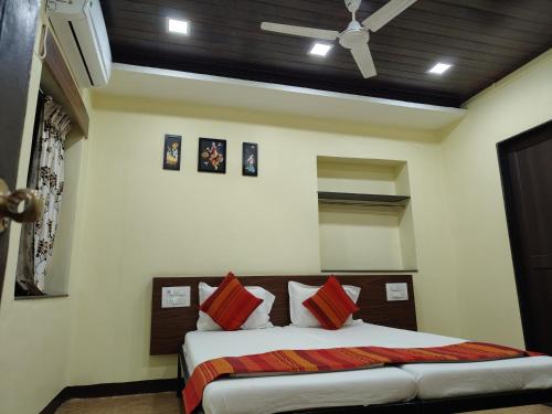 a bedroom with a bed with red pillows and a ceiling at Hotel Bakul in Kolhapur
