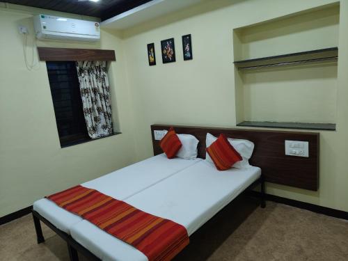 a bedroom with a bed and a window at Hotel Bakul in Kolhapur
