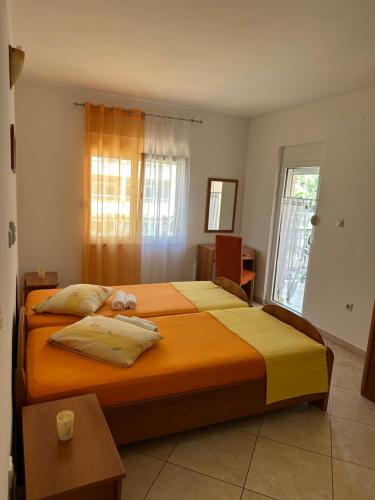 ein Schlafzimmer mit einem großen Bett mit orangefarbener Bettwäsche in der Unterkunft Apartmani Aleks in Budva