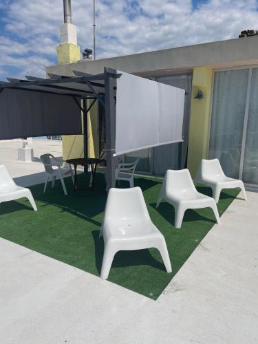 a group of white chairs and a projection screen on a roof at Maria Apartments in Paralia Dionysiou