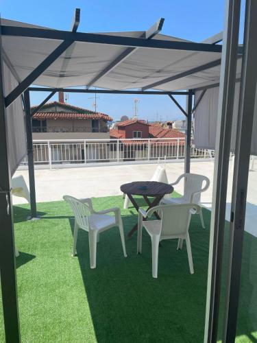 a patio with a table and chairs on the grass at Maria Apartments in Paralia Dionysiou