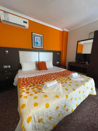 a bedroom with a large bed with an orange wall at Maria Apartments in Paralia Dionysiou