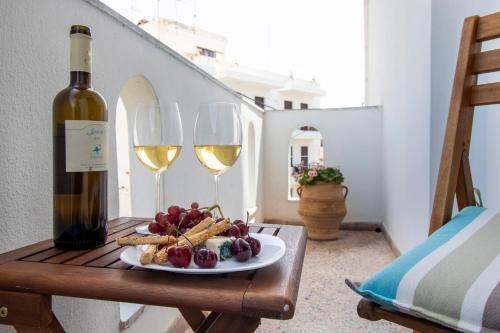a table with a plate of food and two wine glasses at Babilia central appartment suites Limenas Hersonisou in Hersonissos