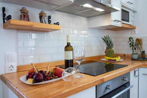 a bottle of wine and a plate of fruit on a kitchen counter at Babilia central appartment suites Limenas Hersonisou in Hersonissos