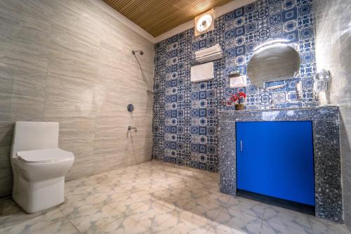 a bathroom with a toilet and a blue door at The Neeraj Ganga Cottages in Rishīkesh