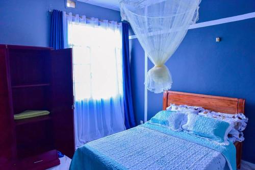 a blue bedroom with a bed and a window at Cagil House in Mutumba
