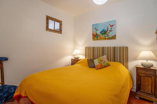 - une chambre avec un grand lit jaune et deux lampes dans l'établissement La Maison des Remparts, à Saint-Jean-de-Barrou