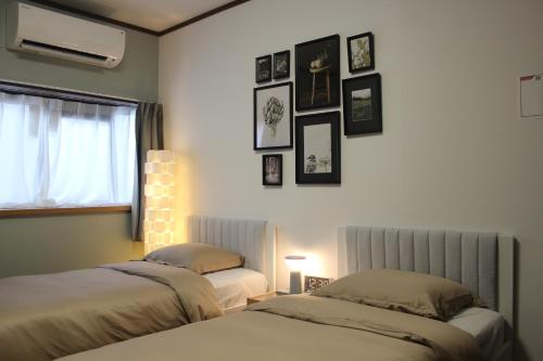 a bedroom with two beds and pictures on the wall at 嵐西成松 in Osaka