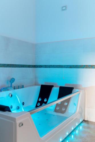 a bathroom with a blue tub with a sink at MILLE SUITE GARDEN in Noto