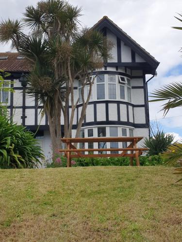 una casa en blanco y negro con un banco delante en San Remo, en Paignton