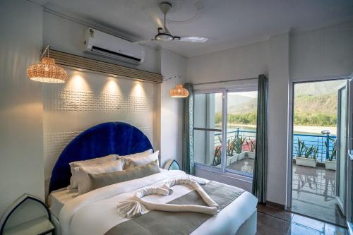 a bedroom with a bed with a blue headboard and a balcony at The Neeraj Ganga Cottages in Rishīkesh