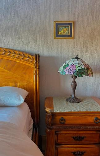 a lamp on a wooden table next to a bed at Le Bouquet Apart Hotel in San Carlos de Bariloche