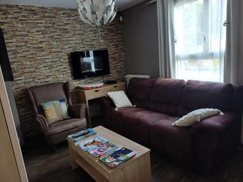 - un salon avec un canapé brun et une télévision dans l'établissement Appartement en centre ville, à Gien