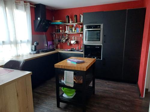 une cuisine avec des murs rouges et une table en bois dans une cuisine dans l'établissement Appartement en centre ville, à Gien