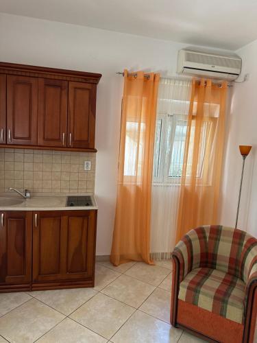eine Küche mit orangefarbenen Vorhängen und einem Stuhl und einem Waschbecken in der Unterkunft Apartmani Aleks in Budva