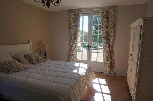 une chambre avec un lit et une grande fenêtre dans l'établissement le Bosc de castang, à Pressignac