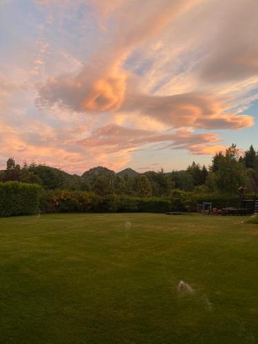a green field with a cloudy sky at sunset at Le Bouquet Apart Hotel in San Carlos de Bariloche