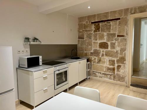 a kitchen with white cabinets and a stone wall at Le poète roucher in Montpellier