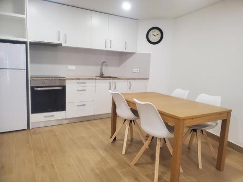 a kitchen with a wooden table and white cabinets at Charming Jasmin House in Viseu