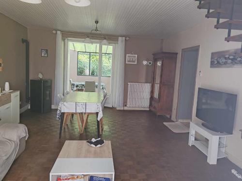 un salon avec une table et une télévision dans l'établissement Maison de campagne, à Gomméville