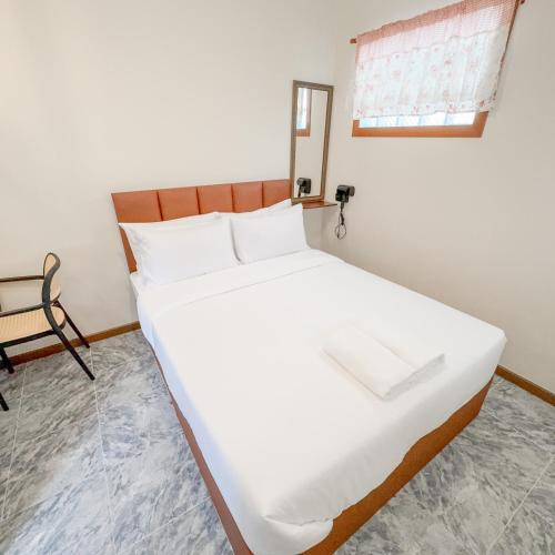a large white bed in a room with a chair at JB Home Bangkok - Victory monument in Bangkok
