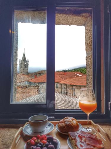 a table with food and a drink and a window at Luz do Sil in Ourense