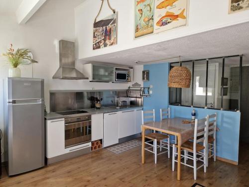 Il comprend une cuisine équipée d'une table, d'un réfrigérateur, d'une table et de chaises. dans l'établissement Appart calme avec vue dégagée, terrasse, clim, parking !, à Sète