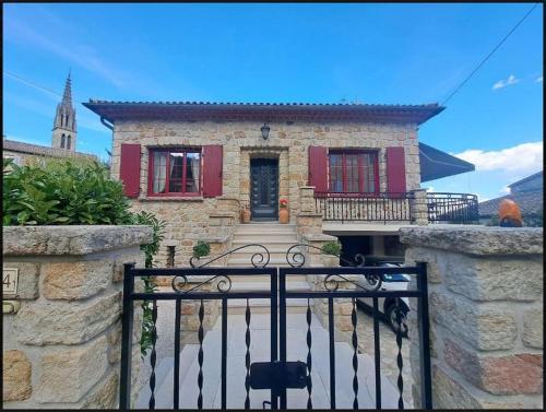 une maison en pierre avec des volets rouges et un portail dans l'établissement La Jolie Maison de Banne, 4 étoiles, piscine privée chauffée, calme, à Banne