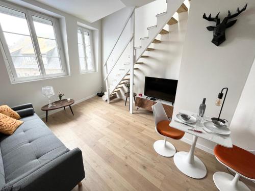 - un salon avec un canapé, une télévision et des escaliers dans l'établissement Duplex avec vue - Intra-muros Design et authenticité, à Saint-Malo