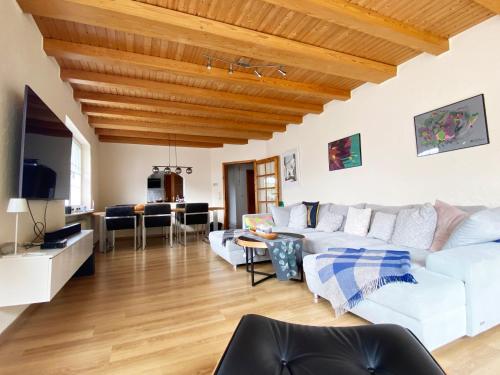 Elle comprend un salon doté d'un mobilier blanc et d'un plafond en bois. dans l'établissement FeWo Sonnenlay - Apartments an der Mosel, à Brauneberg