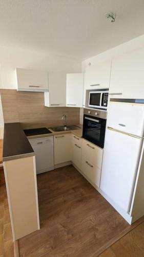 une cuisine avec des armoires blanches et un réfrigérateur blanc dans l'établissement Vue Mer & Plage à 40m à Palavas-les-Flots, à Palavas-les-Flots