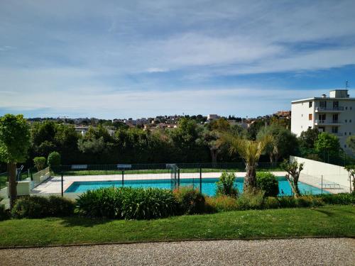 une piscine dans une cour avec un bâtiment dans l'établissement Cosy studio,piscine,parc fleuri,résidence standing,parking, à Antibes