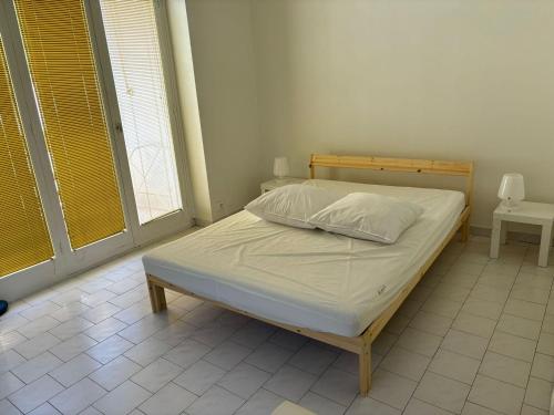 - un lit dans une chambre avec 2 fenêtres dans l'établissement Appartement spacieux avec terrasse face mer à Menton, proche plages et centre-ville - FR-1-196-327, à Menton