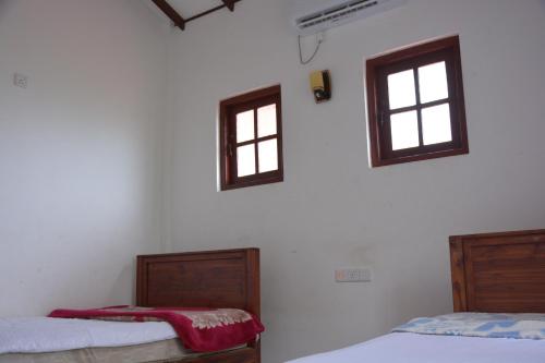two beds in a room with two windows at UR Villa in Waskaduwa