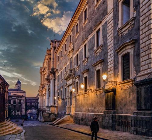 a man walking down a street next to a building at Sweet Home Catania historic center in Catania