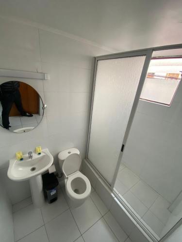 a white bathroom with a toilet and a sink at Hotel Orozco in Antofagasta