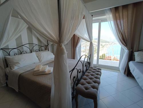 a bedroom with a canopy bed and a chair with a window at Relais Tiaré Bed and Breakfast in Bacoli