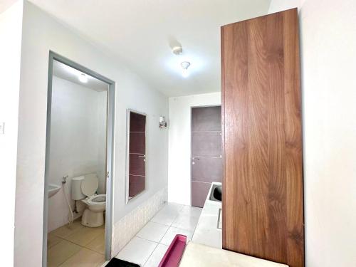 a bathroom with a toilet and a wooden door at Pleasant Tamansari Prospero Studio Apartment in Sidoarjo by Le Ciel Hospitality in Sidoarjo