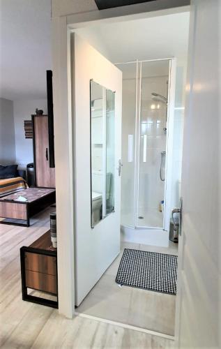 La salle de bains blanche est pourvue d'une douche et d'une porte en verre. dans l'établissement A l'Orée des Pins, Appartement Plage du Tanchet, à La Pironnière