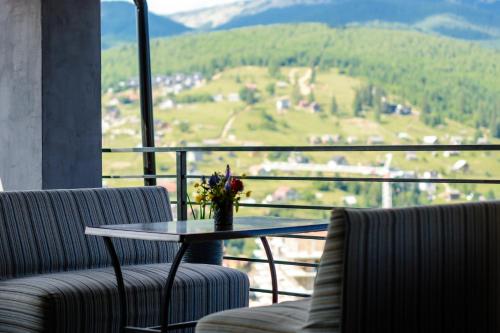 a balcony with two chairs and a table with flowers on it at Севеней Готель in Bukovel