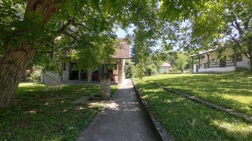a sidewalk in front of a house with a tree at Gorska Vila Sisevac in Sisevac