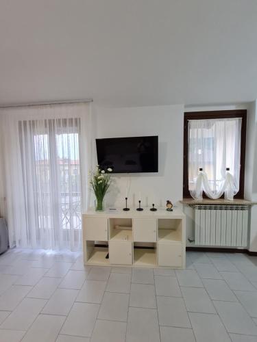 a white living room with a tv and a mirror at Casa Amelia lago Maggiore in Maccagno Inferiore