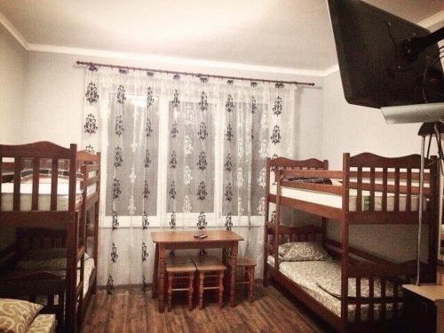 a room with two bunk beds and a table and a television at Hostel Serge in Lviv