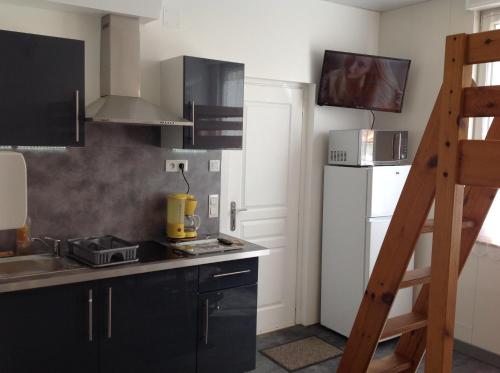 - une cuisine avec des armoires noires et un réfrigérateur blanc dans l'établissement Studio 1 proche mer Dunkerque Malo les bains, à Dunkerque